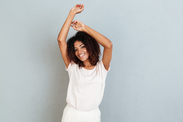 Poster - Cheerful young african woman standing over grey wall