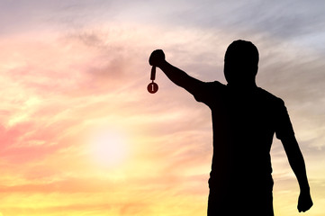 Wall Mural - silhouette of man holding golden medal on sunset background, concept as winner and champion in sport