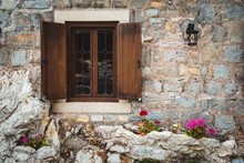 Ancient Stone Wall, Classic Old Window With Wooden Shutters, Street Lantern And Flowers On Petrovac, Montenegro.