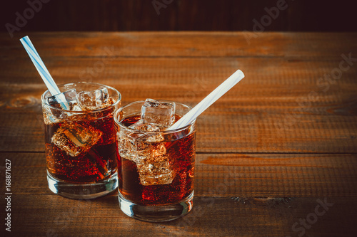 Stampa su Tela Beautiful cold drink of Cola with ice cubes with a boiler straws in glasses on wooden background with free space