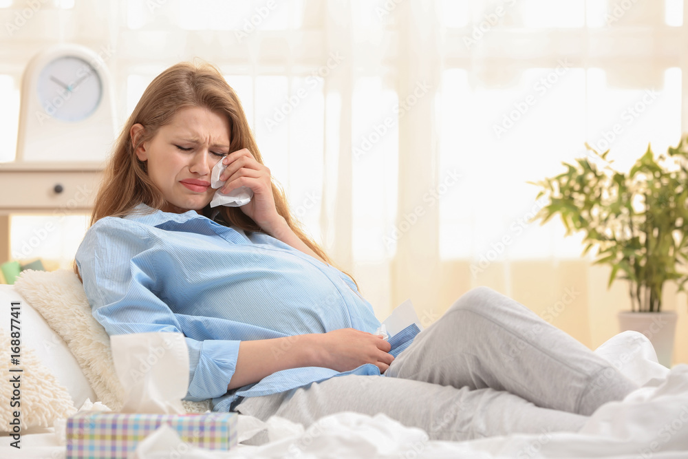 Beautiful pregnant woman crying in light room. Pregnancy hormones concept