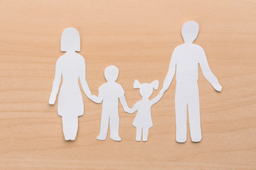 Poster - Paper silhouette of family on wooden background. Life insurance concept