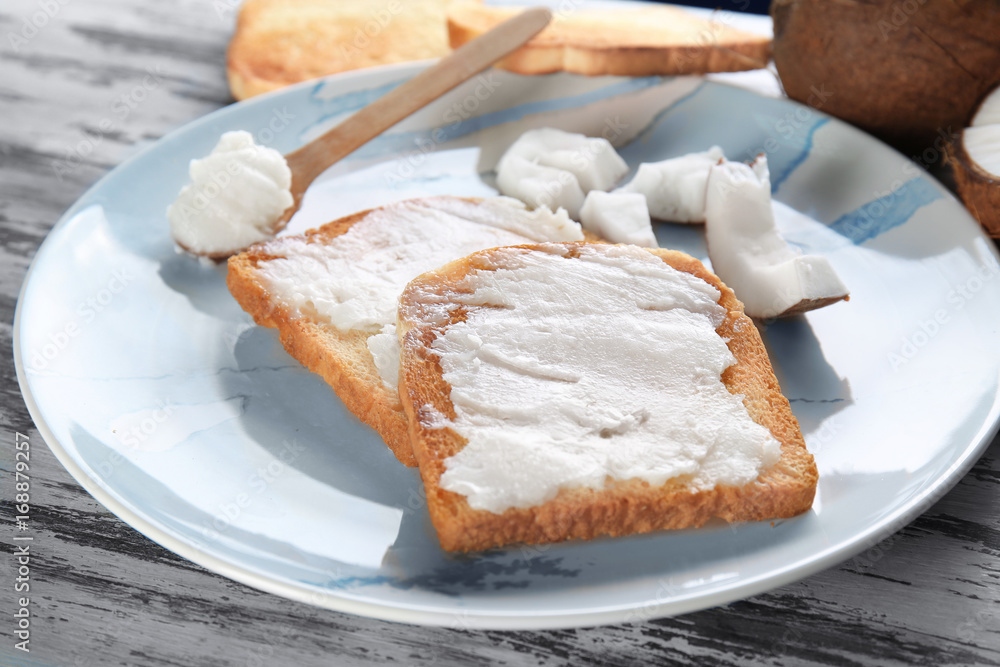 Delicious toasts with coconut oil in plate on table, closeup