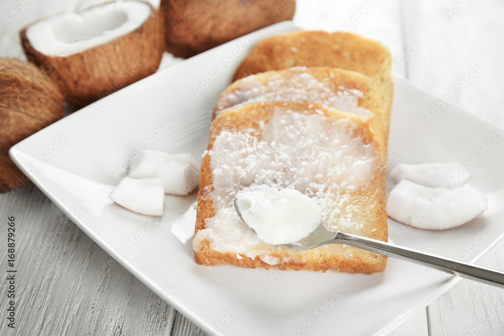 Delicious toasts with coconut oil in plate on table, closeup