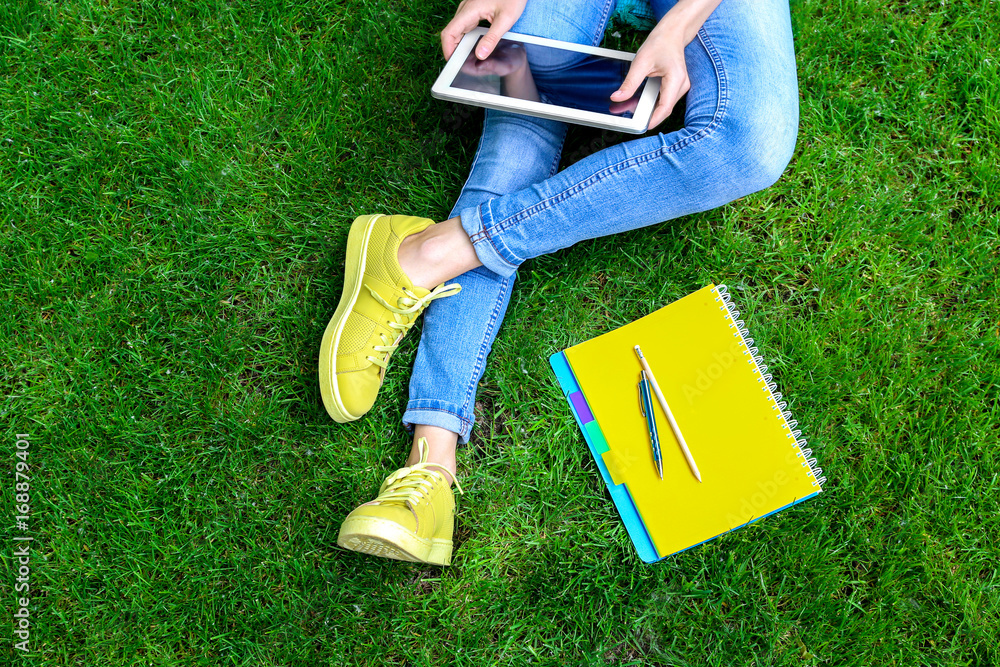 Woman sitting on green grass with tablet