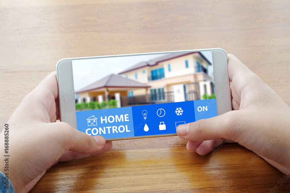 Hand using smart phone with home control device on screen background ...