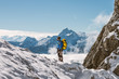 © Nox/Stocksy - male mountaineer with yellow backpack overlooking snowcovered mo