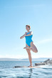 © vitaliymateha - Cheerful sportive woman in yoga pose on edge of pool looking away on background of sea, Iceland.