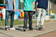 © simonmayer - Two young people walk along a sidewalk next to one who skate