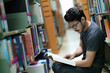 © torwaiphoto - Asian student in the library at bookshelf.She is reading