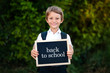 © nfbiruza - Back to school concept. Elementary school student boy holding blackboard background. Cute caucasian primary grade pupil in for first day in education semester