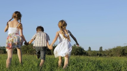 Wall Mural - Three happy children playing in the field at the day time. Kid having fun outdoors. Concept of happy game.