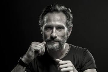 Poster - Black and white portrait of self confident brutal man. Mid aged male showing fists on black background.