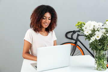 Poster - Smiling african woman sitting by the table