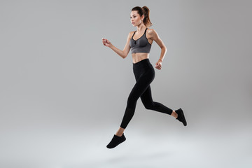 Canvas Print - Side view full length portrait of a young fitness woman running