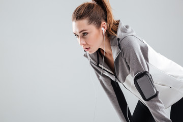 Wall Mural - Close up portrait of a tired young sportswoman in earphones