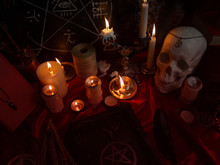 Witchcraft Composition With Human Skull, Burning Candles, Magic Book, Amulets And Pentagram Symbol. Halloween And Occult Concept, Black Magic Ritual. 