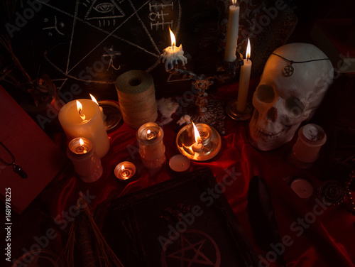 Witchcraft composition with human skull, burning candles, magic book, amulets and pentagram symbol Poster
