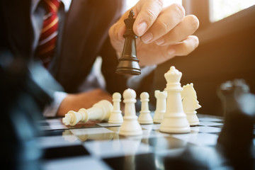 Wall Mural - businessman playing chess on board in office, strategy and competition concept