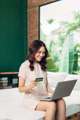 Beautiful asian woman holding a credit card and purchasing online