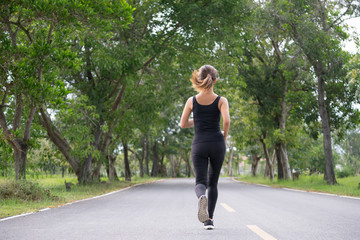 Wall Mural - Young fitness sport woman running on the road in the morning, Selective focus.
