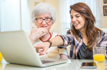 Granddaughter showing her grandmother something on laptop.