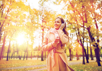 Wall Mural - woman with smartphone and earphones in autumn park