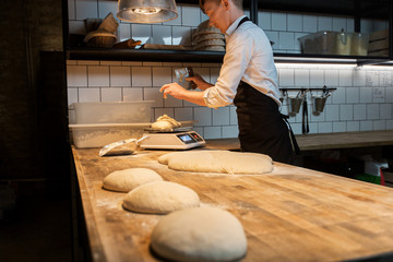 Wall Mural - chef or baker weighing dough on scale at bakery