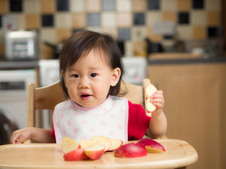 Wall Mural - baby girl eating apple at home