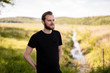 © _robbie_ - Laid back bearded man wearing a black shirt, standing outdoors on a sunny summer day looking away from camera with a smile on his face.