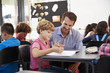 © Monkey Business - Teacher and young school boy looking at notebook in class