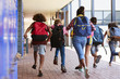 © Monkey Business - School kids running in elementary school hallway, back view