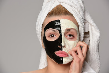 beautiful female model with black and white facial cosmetic mask posing. Isolated on gray background.