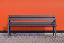 Wooden Street Bench On The Background Of An Orange Wall