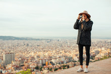 Woman Taking A Photo With Her Vintage Camera Of Cityscape.