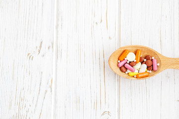 Wall Mural - Many pills in a wooden spoon. Background. The concept of colds, illness, treatment, lifestyle.