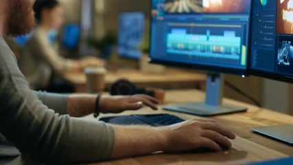 Wall Mural - male videographer edits and cuts footage and sound on his personal computer with two displays. his o