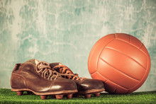 Retro Outdated Soccer Spike Boots And Football. Vintage Old Style Filtered Photo