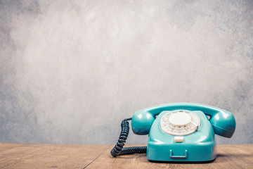 Fototapete - Retro old mint green telephone on wooden table front textured grunge concrete wall background. Vintage instagram style filtered photo