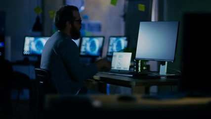Wall Mural - on a early morning mobile application developer sits at his desk and starts working, he is alone in 