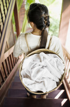 A Chamber Maid Carries Room Towels In A Basket On Her Back At 3 Nagas By Alila Hotel. Luang Prabang, Laos.