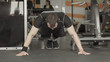 © lenblr - Sportsman wearing black shorts and t-shirt doing push-ups in gym.
