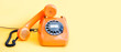 Vintage phone busy handset receiver on yellow background. Retro style orange telephone communication call center concept. Shallow depth field. copy space template