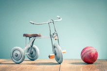 Old Retro Toy Bicycle With Three Wheels And Red Leather Ball. Vintage Instagram Style Filtered Photo
