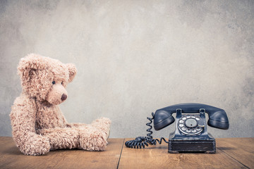 Fototapete - Teddy Bear toy and old retro black rotary telephone front concrete wall background. Vintage instagram style filtered photo
