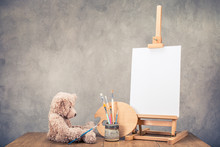 Teddy Bear Toy, Portable Desk Easel For Painting With Canvas Blank, Brushes And Artist's Palette On Wooden Table Front Concrete Wall Background. Retro Instagram Old Style Filtered Photo