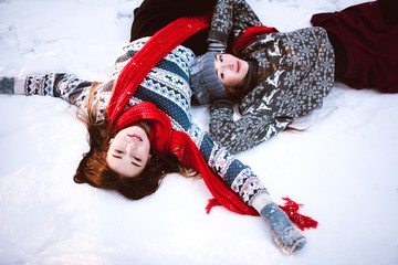 Close up fashion portrait of two sisters hugs and having fun winter time,wearing pink hats, rabbit ears and sweater,best friends couple outdoors, snowy weather