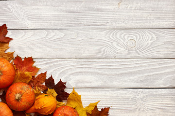 Wall Mural - Autumn leaves and pumpkins over old wooden background