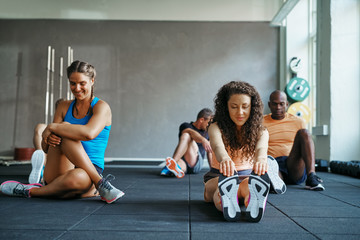 Wall Mural - Smiling young women stretching before a gym workout