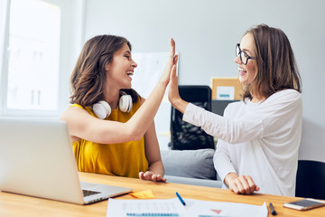 Canvas Print - Sharing happy moments. Two ecstatic young startup businesswomen doing a high five celebrating their success in home office